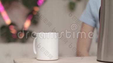 木桌上摆着白色的杯子和电<strong>热水壶</strong>，背景上有年轻女子的轮廓